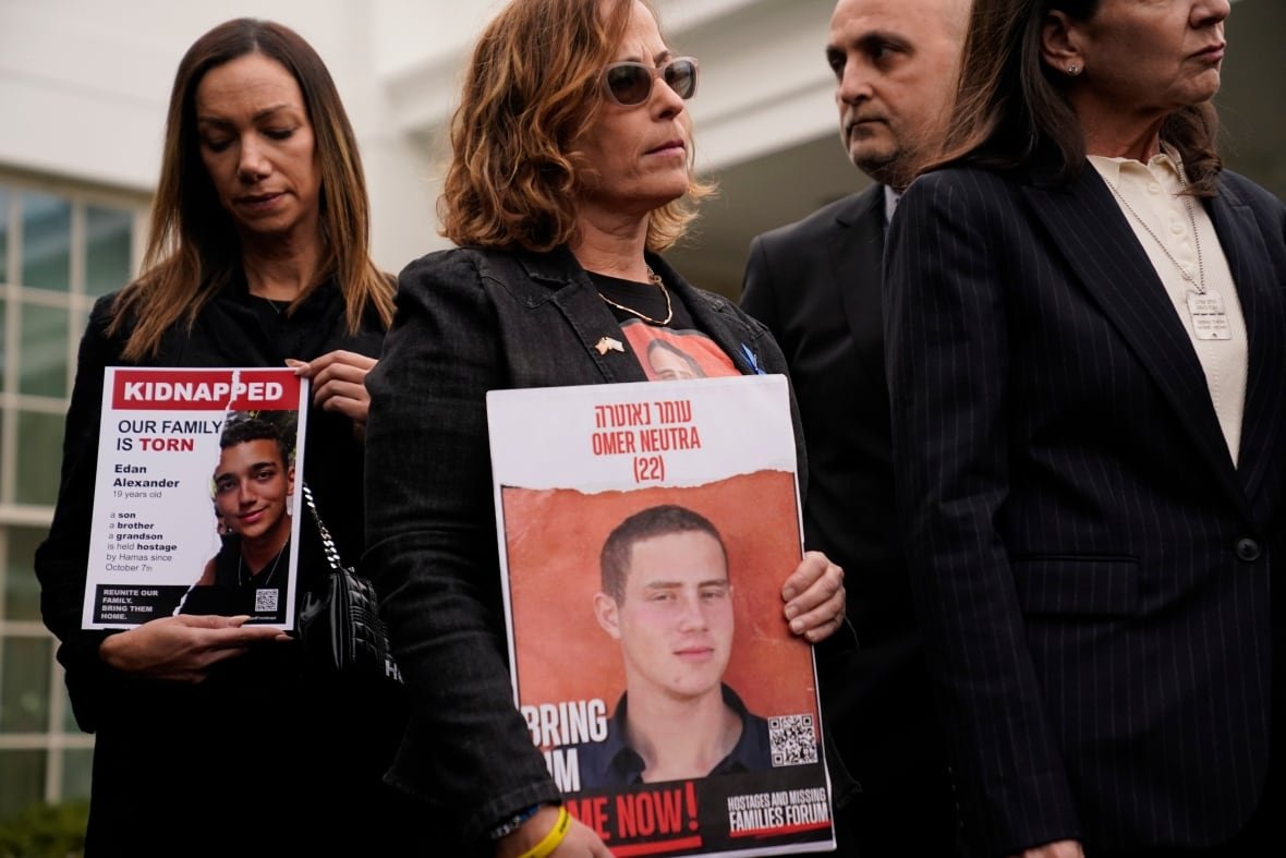 A woman wearing an all-black suit holds up a photo of her son, who was kidnapped.