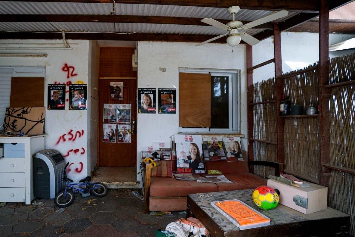 Photos of a missing family are plastered to the white walls of their home. Other belongings, like a couch and a soccer ball, are visible outside the home.