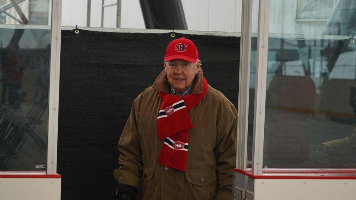 A man wearing a Montrela Canadiens hat and scarf walking onto an ice rink.