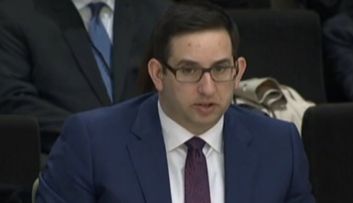 andre-tremblay Bespectactled and seated man talks into microphone.