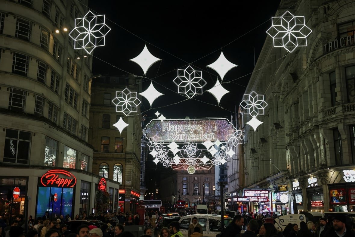 Decorative lights are switched on in central London to celebrate the start of Ramadan, with people and vehicles milling about at night.