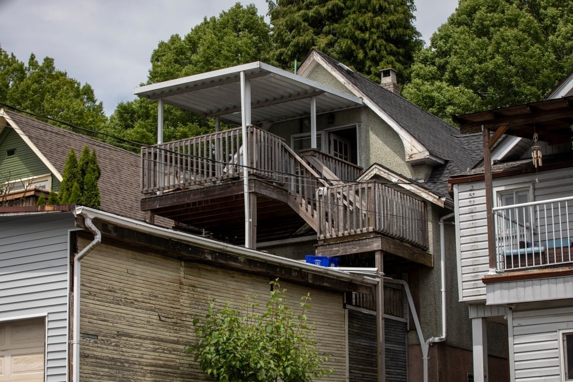 1836-e-1st The back of old house, with an outdoor staircase that leads up to a third-floor wooden patio.