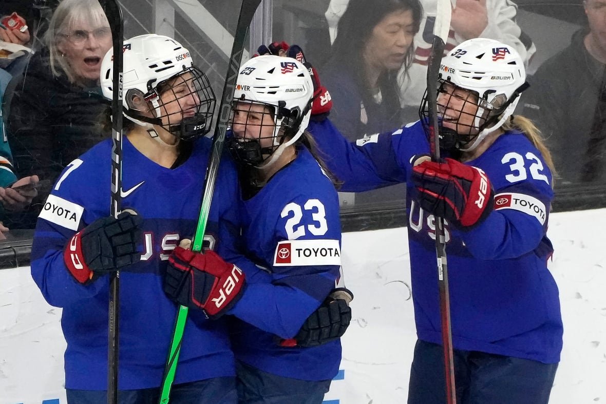 canada-us-hockey-1 Three hockey players wearing blue USA Hockey jerseys celebrate on the ice.