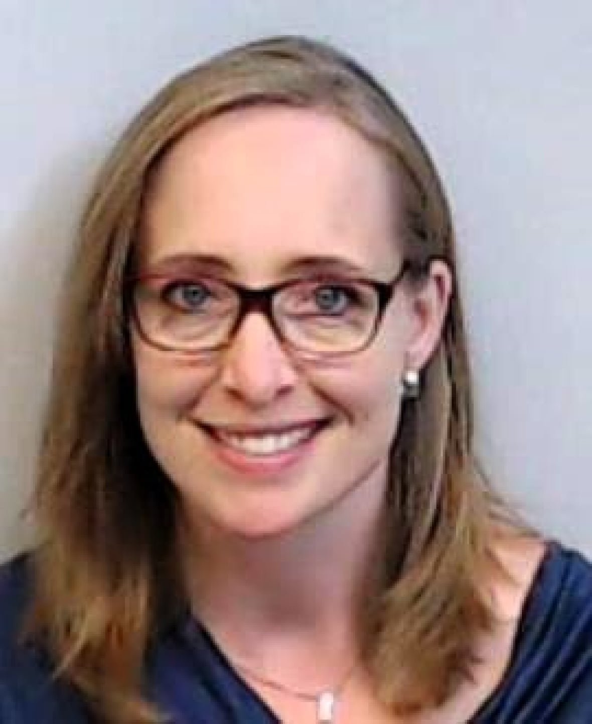 dr-amber-reichert-neonatologist-edmonton Amber is wearing a blue shirt and glasses as she smiles at the camera