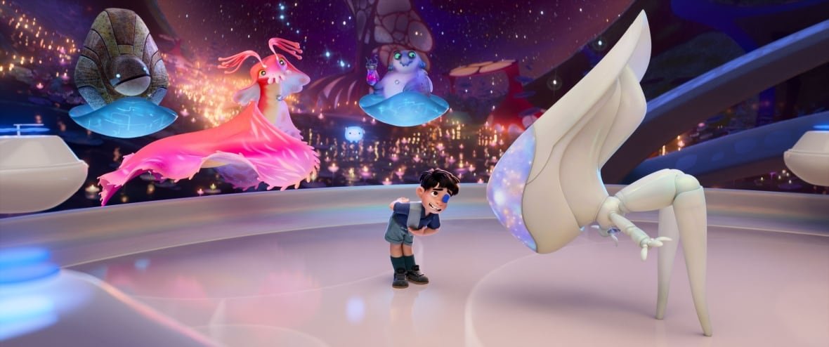 elio-3 An animated image is shown. In it, a little boy standing on a platform boys in front of a robotic figure. Behind him are other aliens floating in the air.