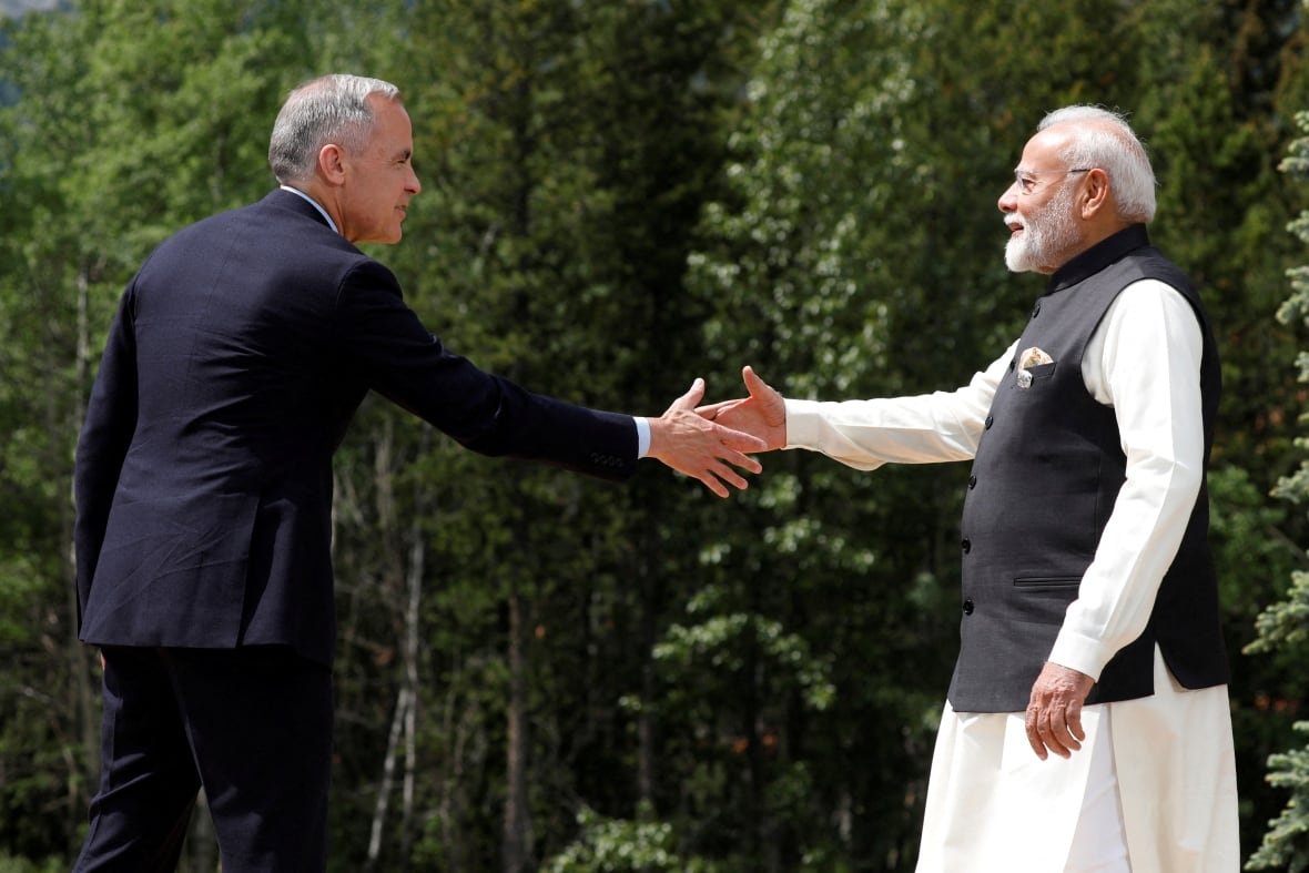 g7-summit-canada-india Two men reach to shake hands.