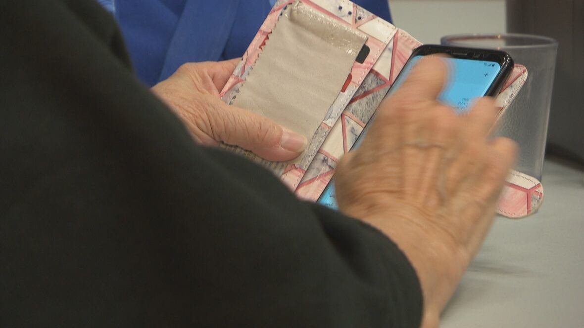 seniors-connect-n-s An elderly person holds a cellphone in her hand.
