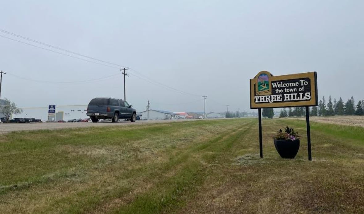 three-hills-sign town welcome sign, as a truck rolls by