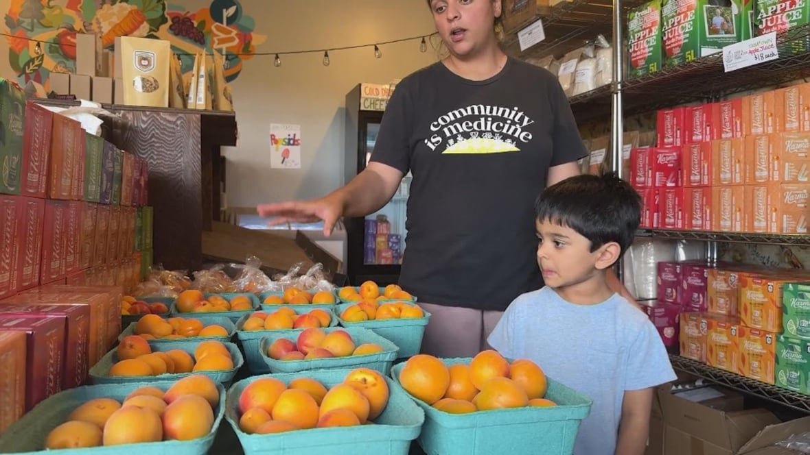 jennifer-deol-peaches A woman points to buckets of peaches as a boy looks on.