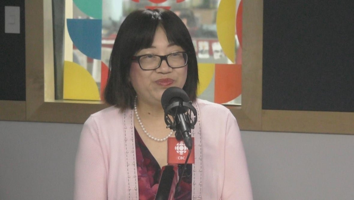 An East Asian woman smiles in a radio studio.