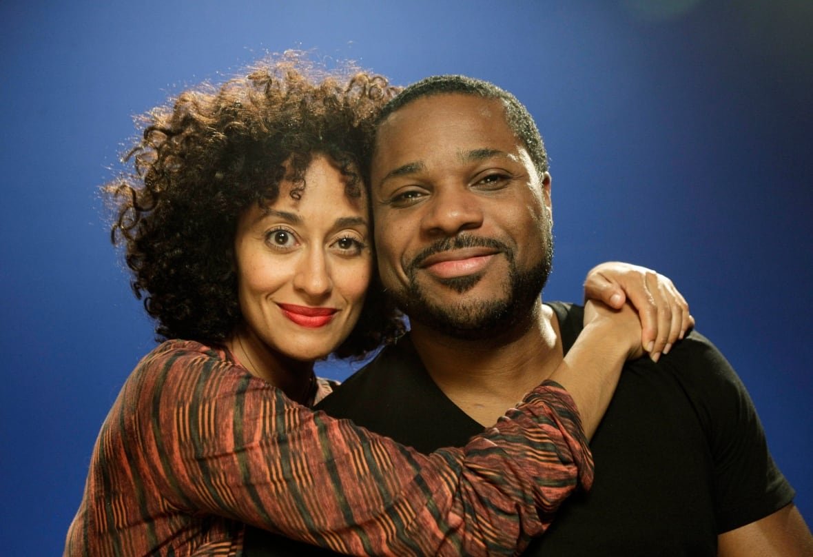 malcolm-jamal-warner-reed-between-the-lines A woman with a striped blouse and curly hair wraps he arms around the shoulders of a man wearing a black t-shirt.