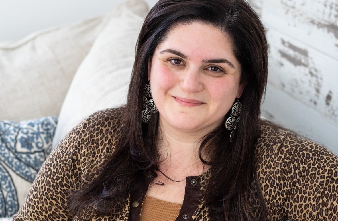 olivia-howell-fresh-starts A woman sits on a sofa, smiling for the camera