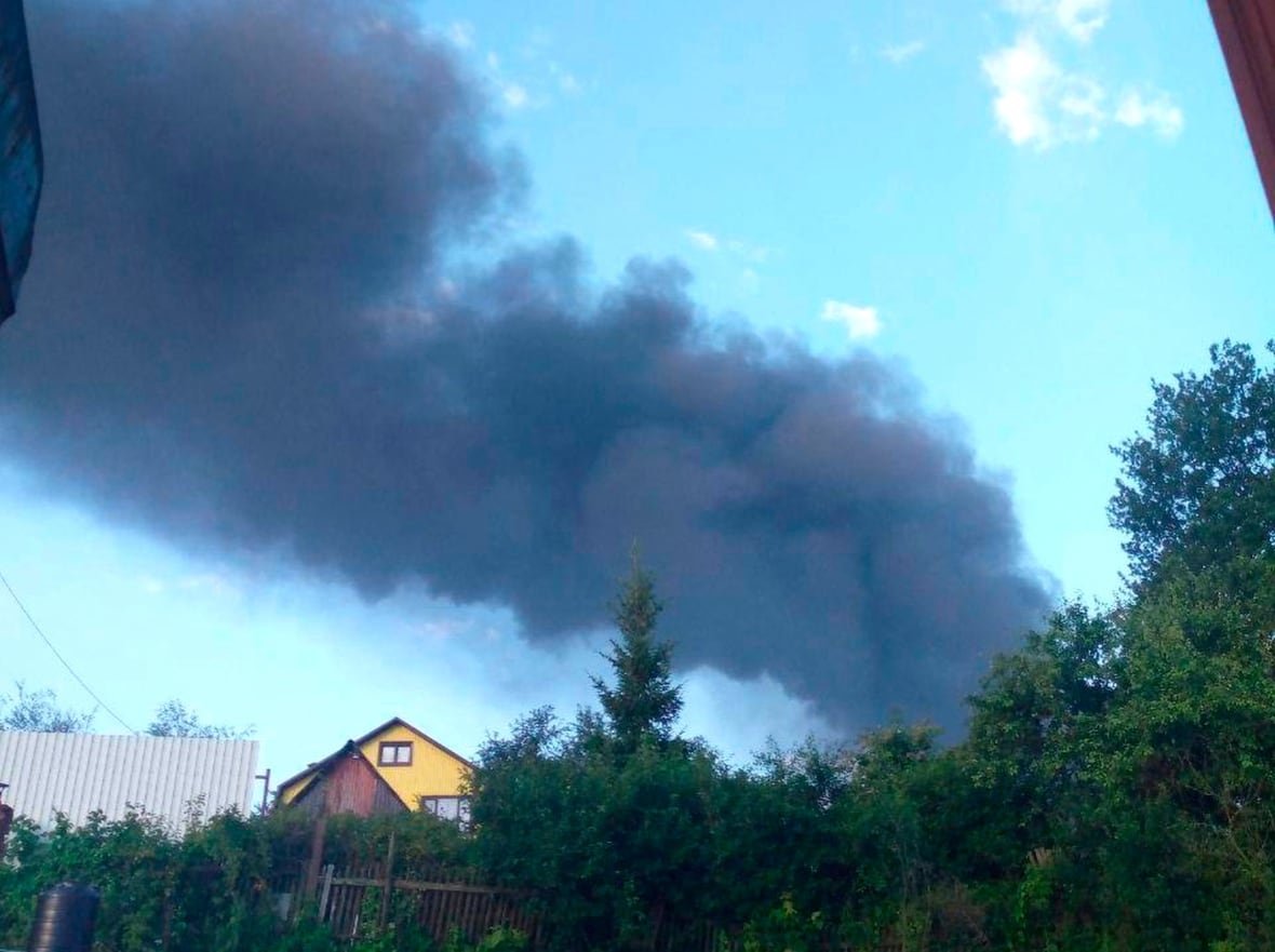 russia-ukraine-drone-attack Large clouds of grey and black smoke are shown in a bright blue sky above what appears to be a residential structure.
