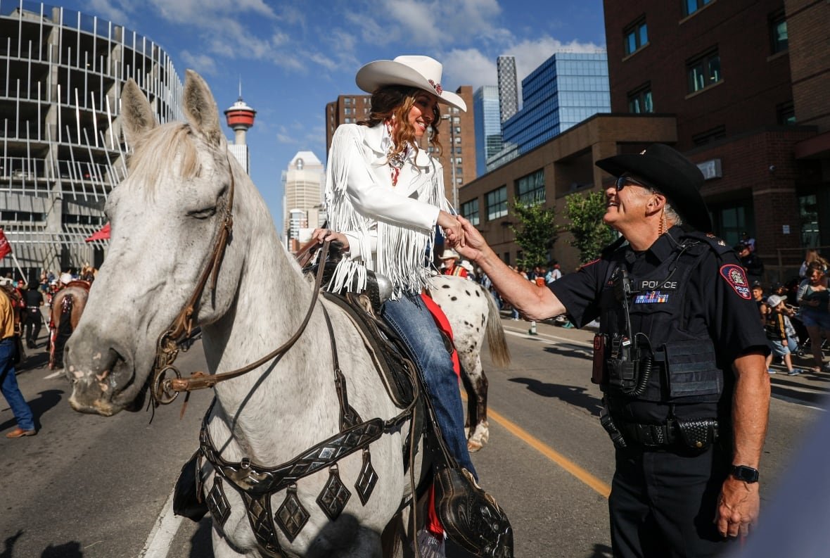 Shania Twain, left, meets a Calgary Police Service officer while she rides a horse during the Calgary Stampede parade.