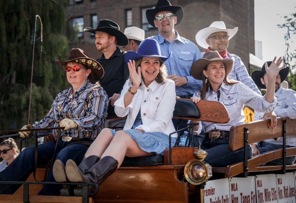 Alberta Premier Danielle Smith, centre, waves from a float.