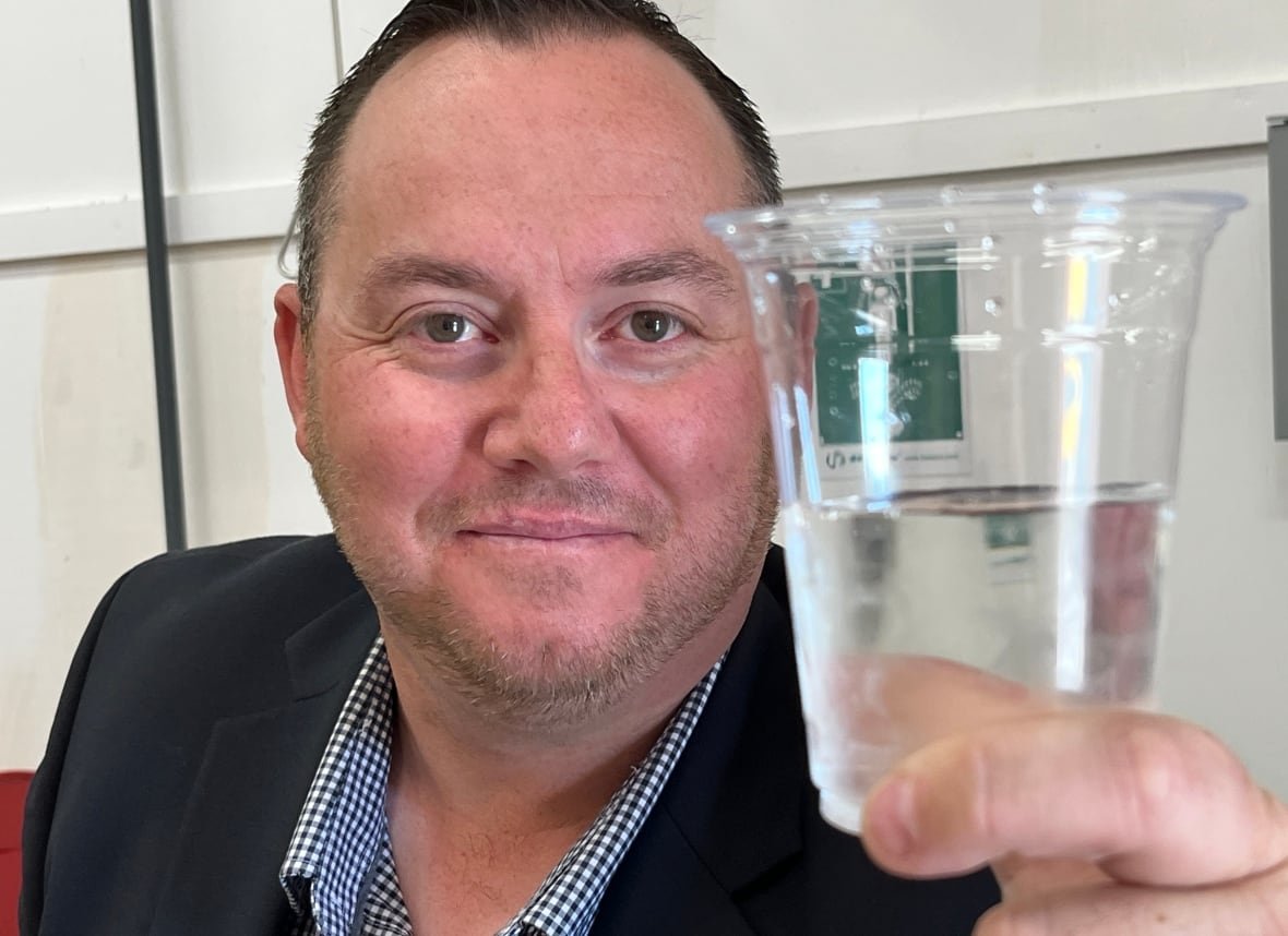 wabana-mayor-water-1 a smiling man holds up a glass of drinking water