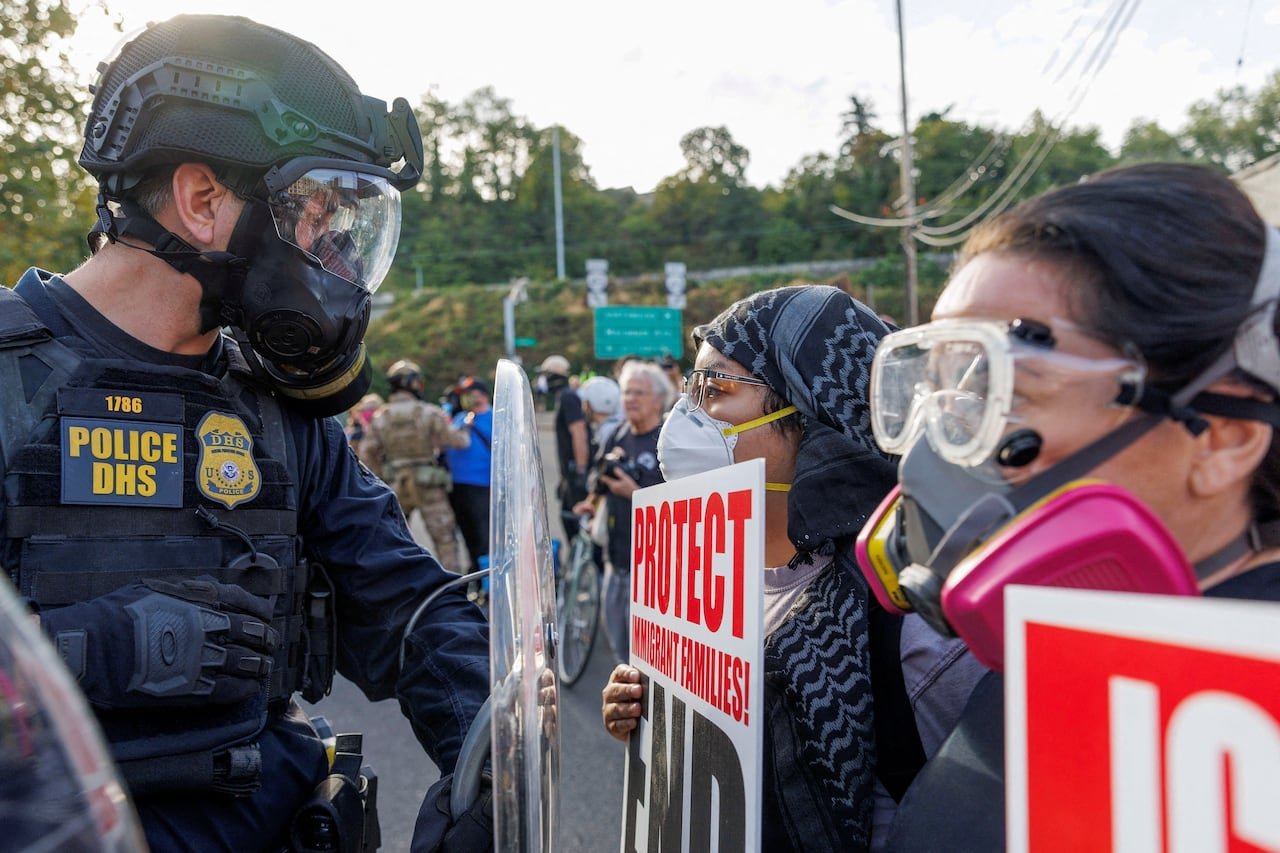 default-932 Police in riot gear face off with protesters wearing personal protective equipment.