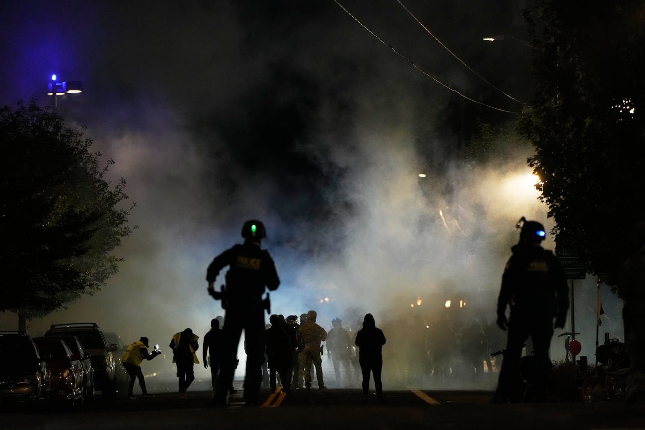 default-935 Law enforcement officers stand guard after deploying tear gas.