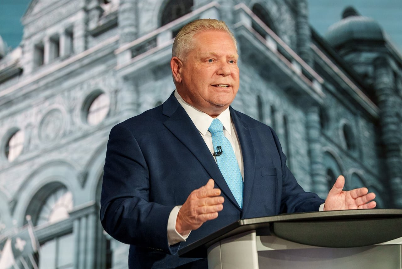 A man stands at a podium and gestures with both of his hands.