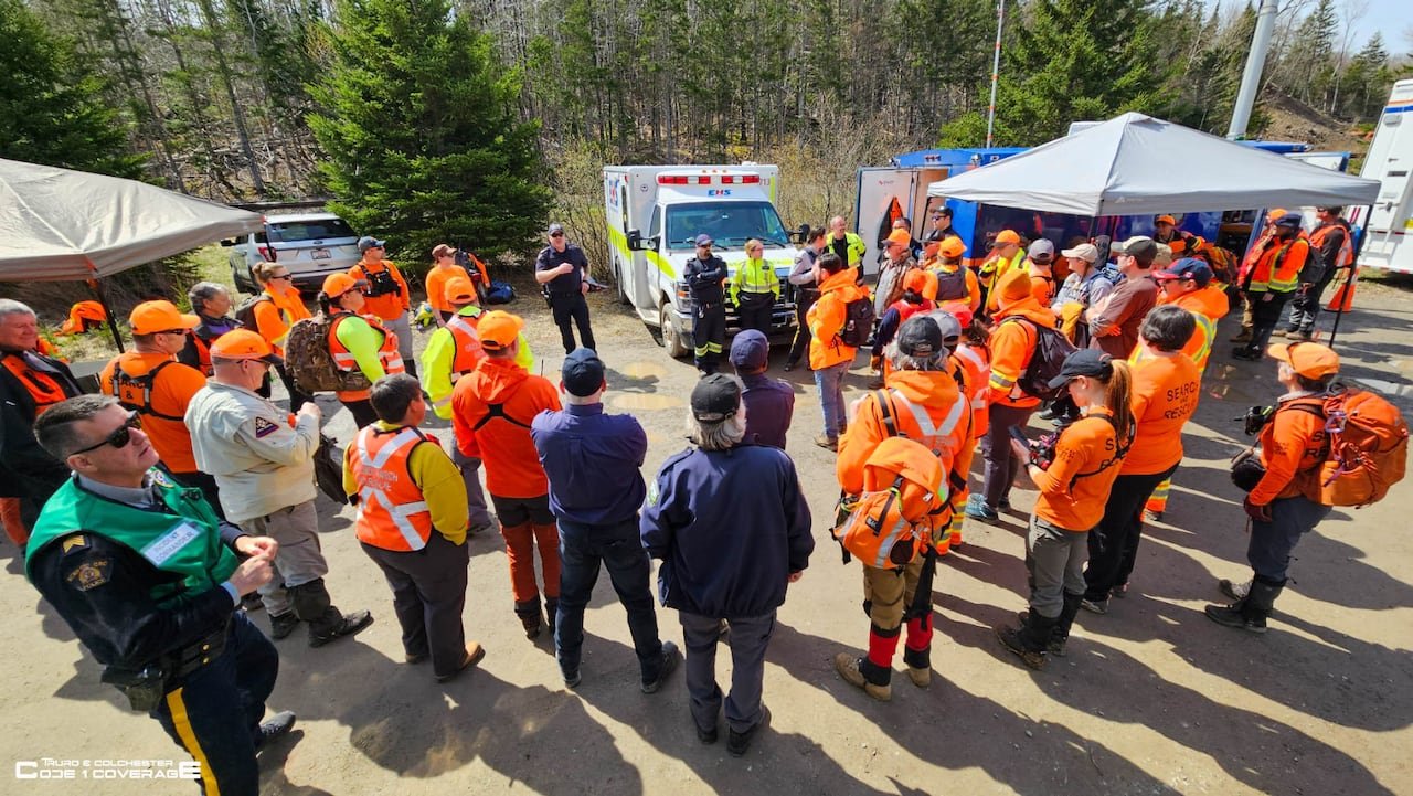 A group of people in bright orange are gathered outside.
