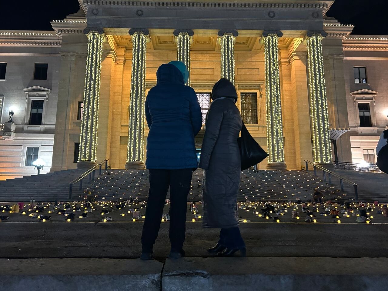 default-3244 Two individuals standing on the steps of a building surrounded by candlelight.