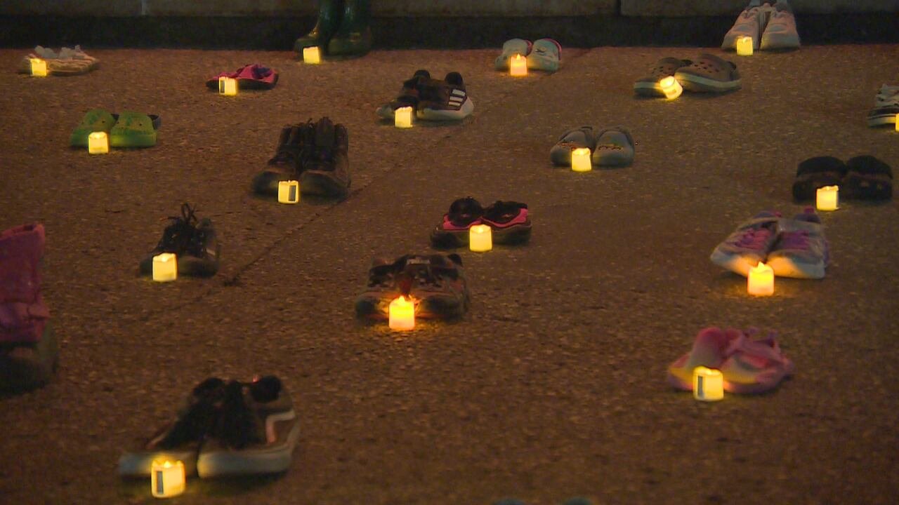 default-3245 Multiple children's shoes illuminated by candles on the steps of a building.