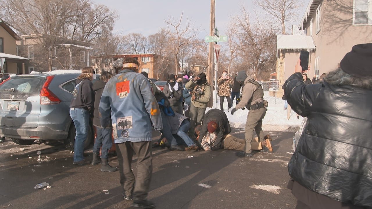 A woman throws herself on top of a man ICE was trying to detain Monday in Minneapolis at an immigration traffic stop. ICE called the confrontation a “riot” and called Hennepin County Sheriff's Department for assistance