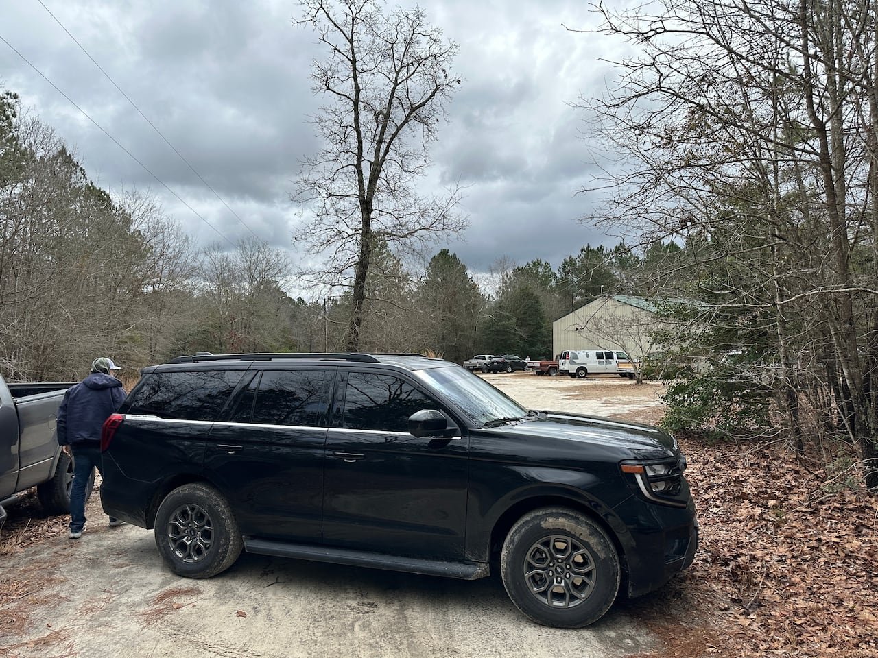 A vehicle is shown in what appears to be a rural property, with a house shown far in the background.