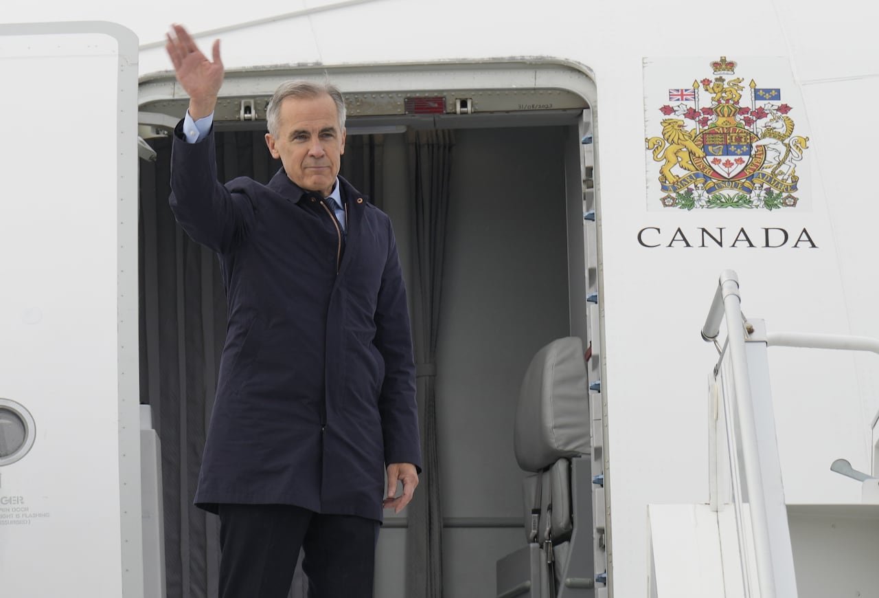 default-178 Carney waves from outside the door of a Canadian government airplane.