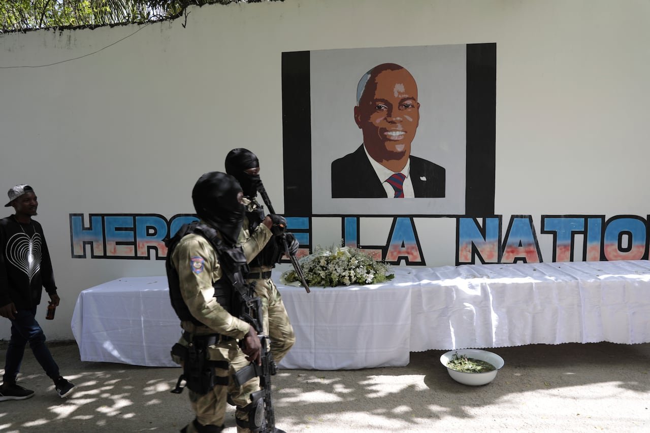default-83 Armed police officers are shown near a mural portraying a dark-complected person.