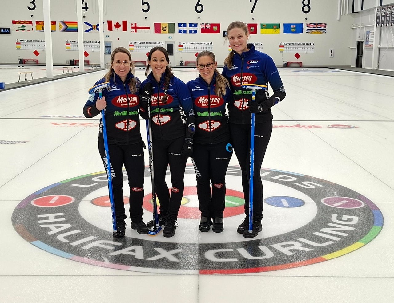 Four women curlers wearing matching outfits are shown posing for a group photo.